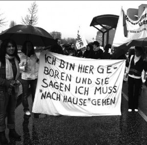 Frauen mit einem Transparent mit der Aufschrift: Ich bin hier geboren und sie sagen ich muss »nach Hause« gehen